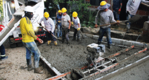 Hormigón en proceso de mezcla y alisado por trabajadores en construcción, usando equipo y herramientas para pavimentar calles en Huila, Colombia.