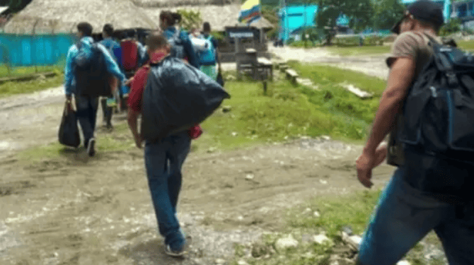 1. personas caminando con mochilas en un entorno rural en Huila, Colombia, en una comunidad local 2. Comunidad en Huila, Colombia, realizando actividades cotidianas al aire libre en un entorno rural 3. Imagen de habitantes del Huila en Colombia transitando por un área rural, reflejando la cultura y vida cotidiana en la región, ideal para contenido relacionado con Medellín TV y noticias locales.