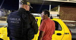 Policía y ciudadano en intercambio frente a una patrulla amarilla en Huila, Colombia, durante la noche, resaltando la presencia policial en la región.