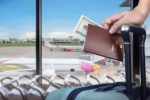 stock-photo-close-hand-holding-thai-passport-dollars-airplanes-airport-terminal-background
